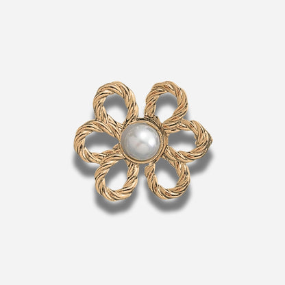 Gouden bloemvormige broche met een centrale parel op een lichtgrijze achtergrond