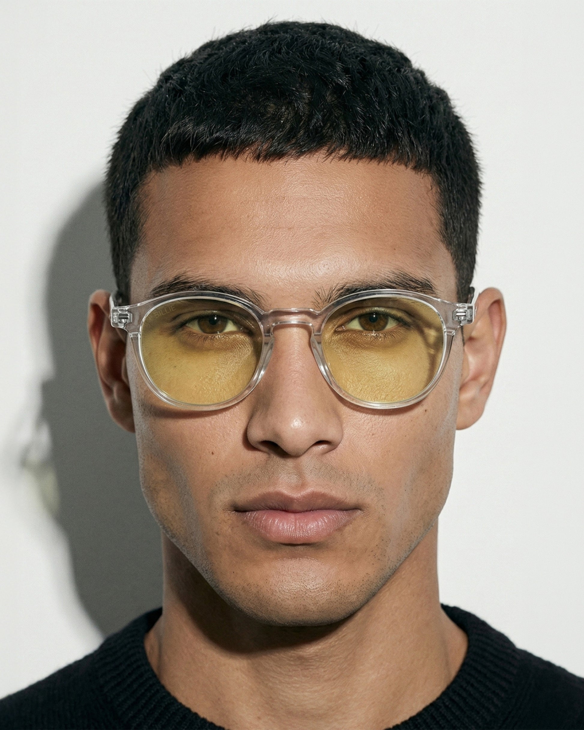 Person with short hair wearing clear glasses with yellow lenses, facing forward.