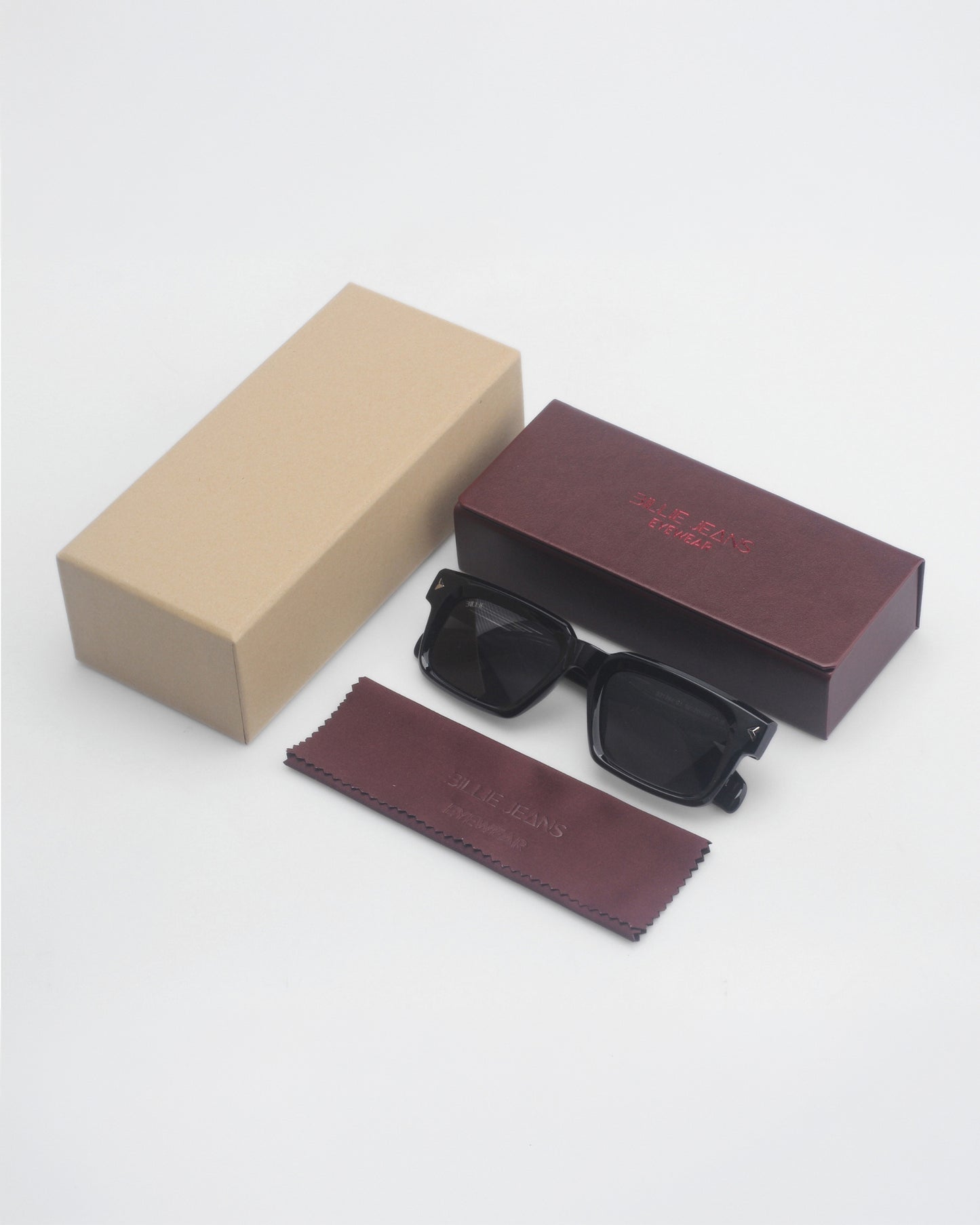 Black sunglasses with a cleaning cloth and two boxes, one brown and one beige, on a light background.