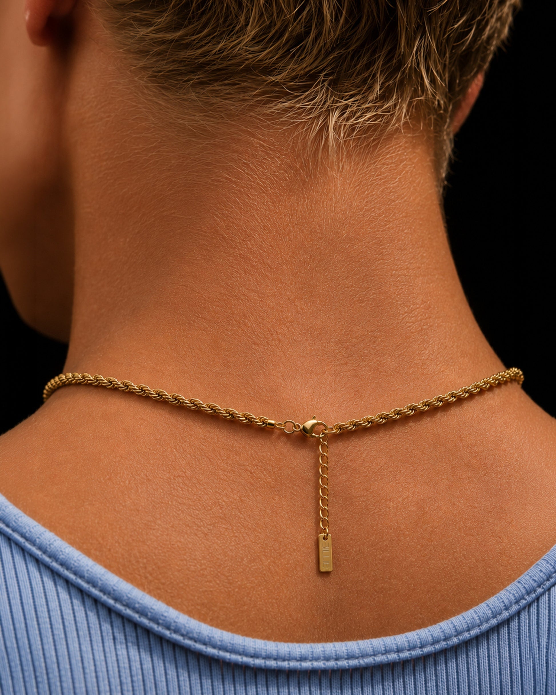Close-up of a gold chain necklace on the back of a person's neck.