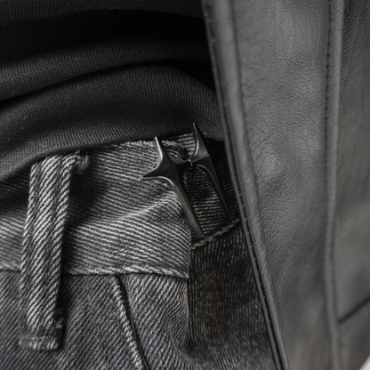 Close-up of a leather jacket with a button and belt buckle detail.