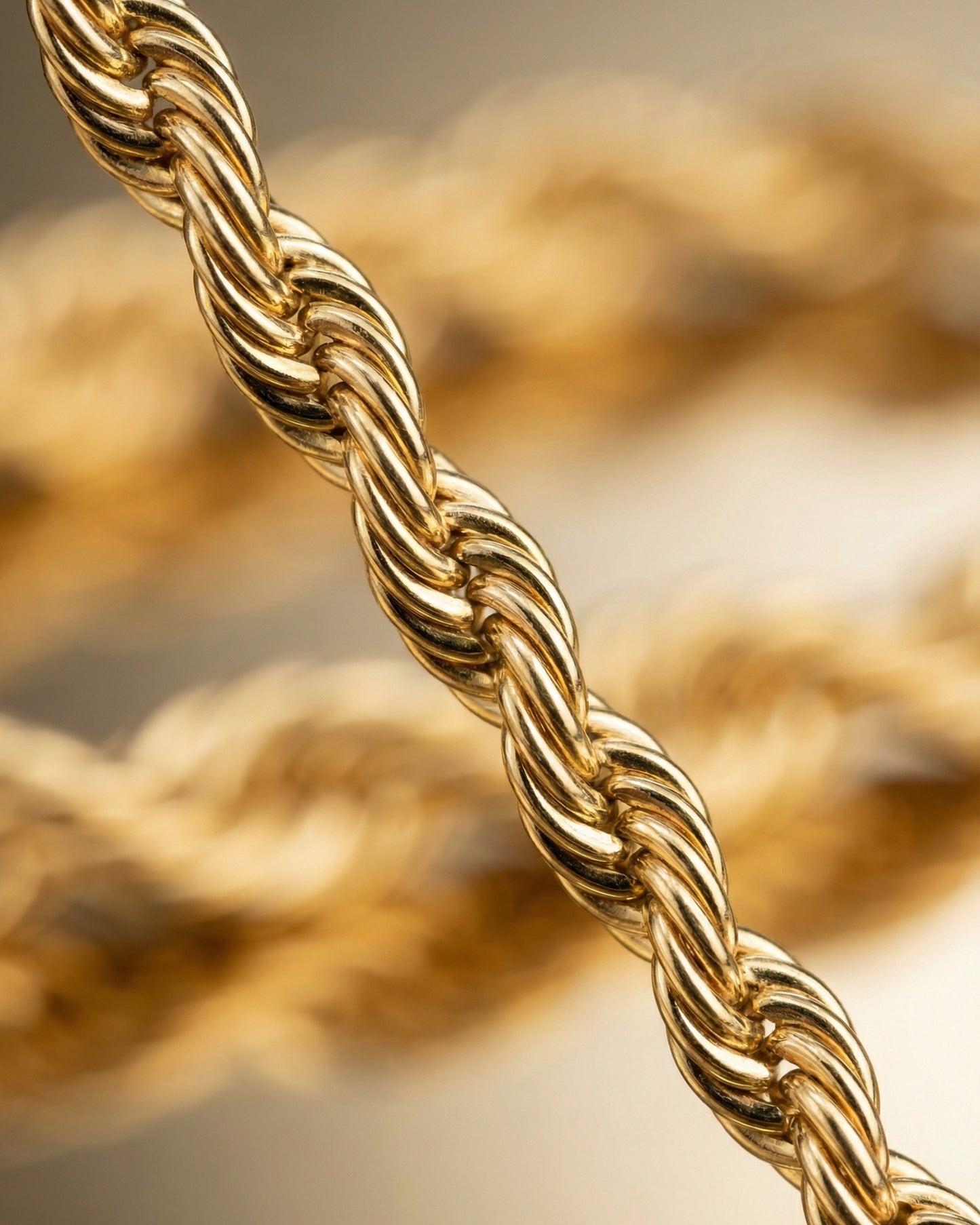 Close-up of a twisted gold chain with a blurred background.