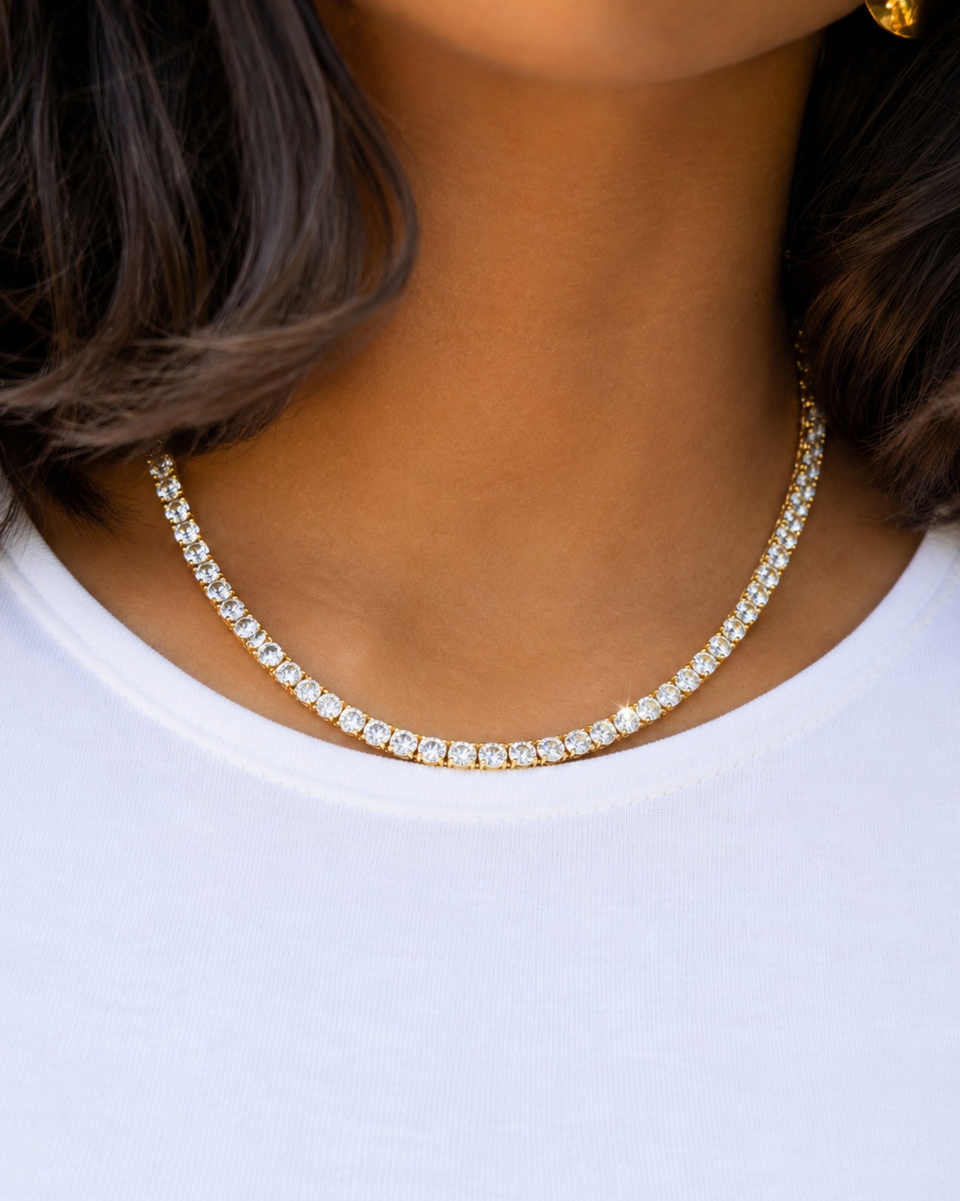 Close-up of a necklace with clear stones worn on a white shirt.
