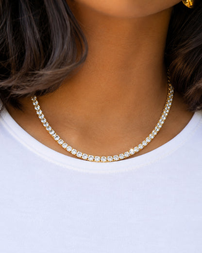 Close-up of a necklace with clear stones worn on a white shirt.