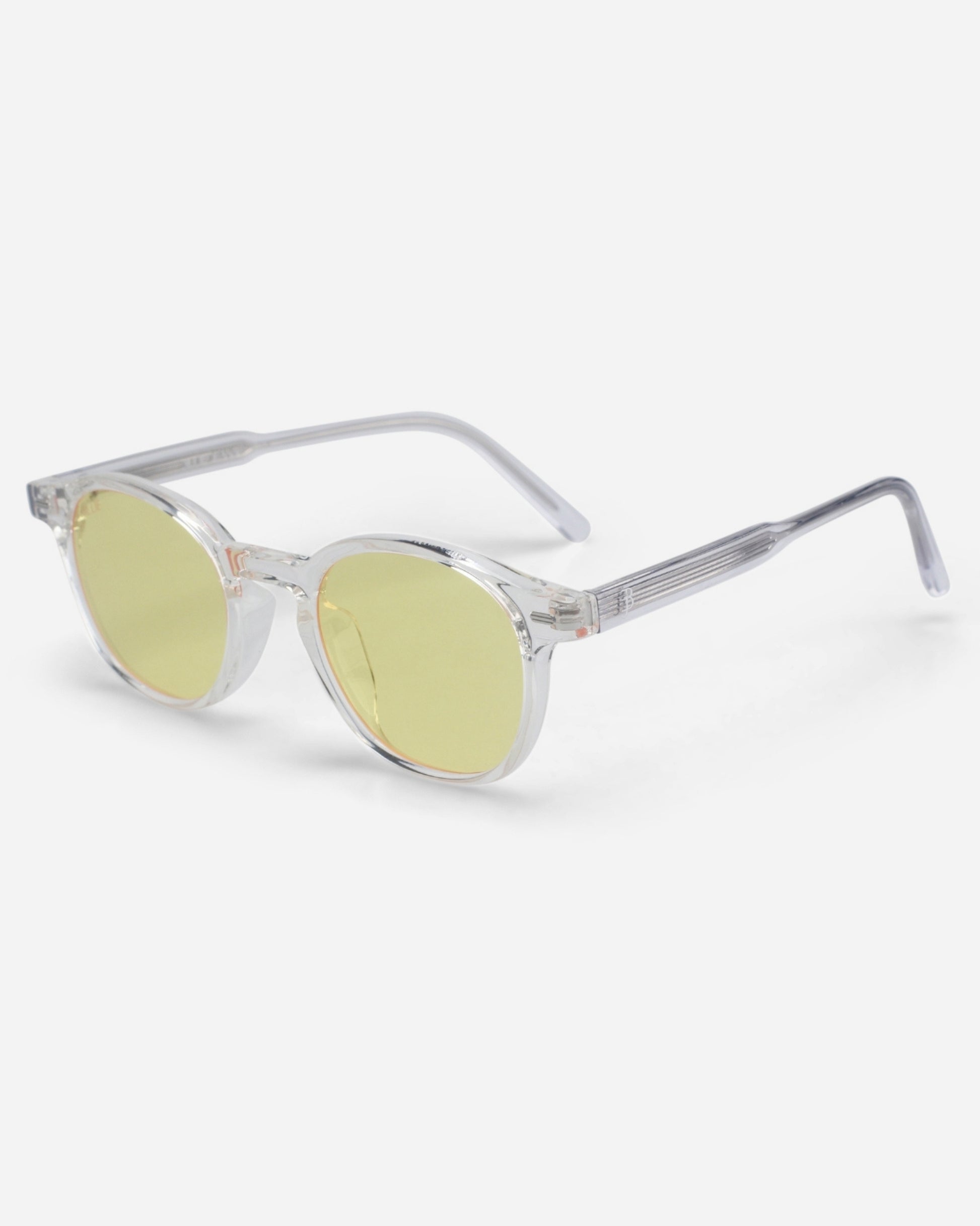 Clear frame sunglasses with yellow lenses on a plain background