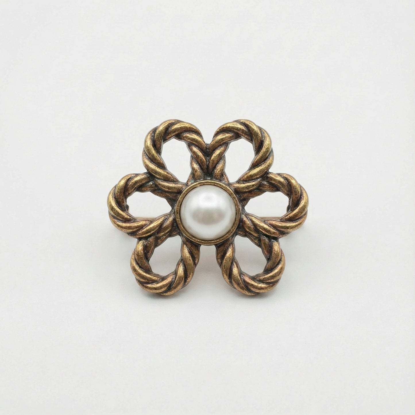 Bronze flower-shaped brooch with a pearl center on a white background