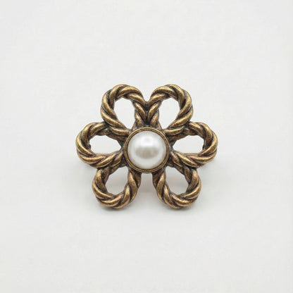 Bronze flower-shaped brooch with a pearl center on a white background