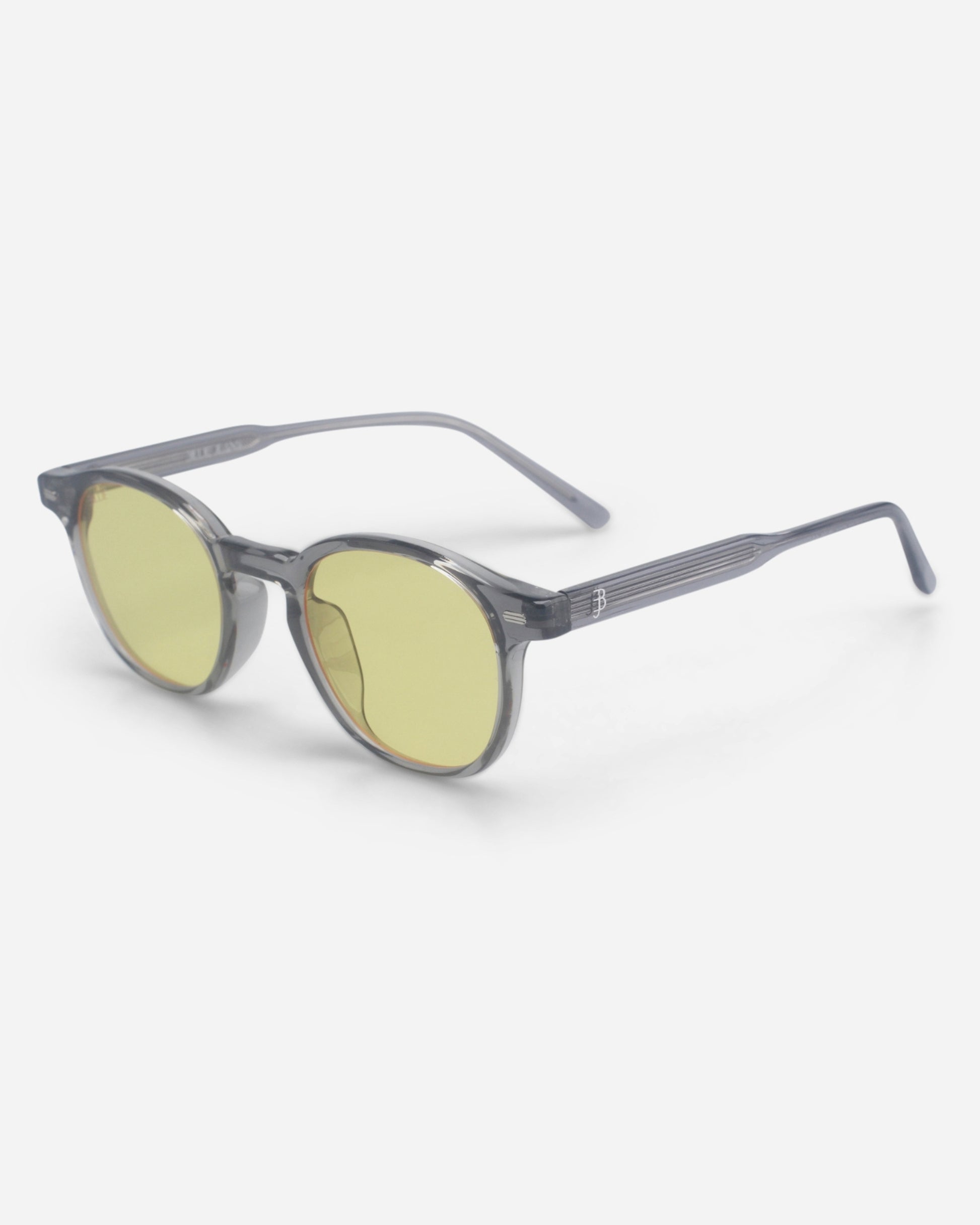 Round sunglasses with yellow lenses and gray frames on a plain background.
