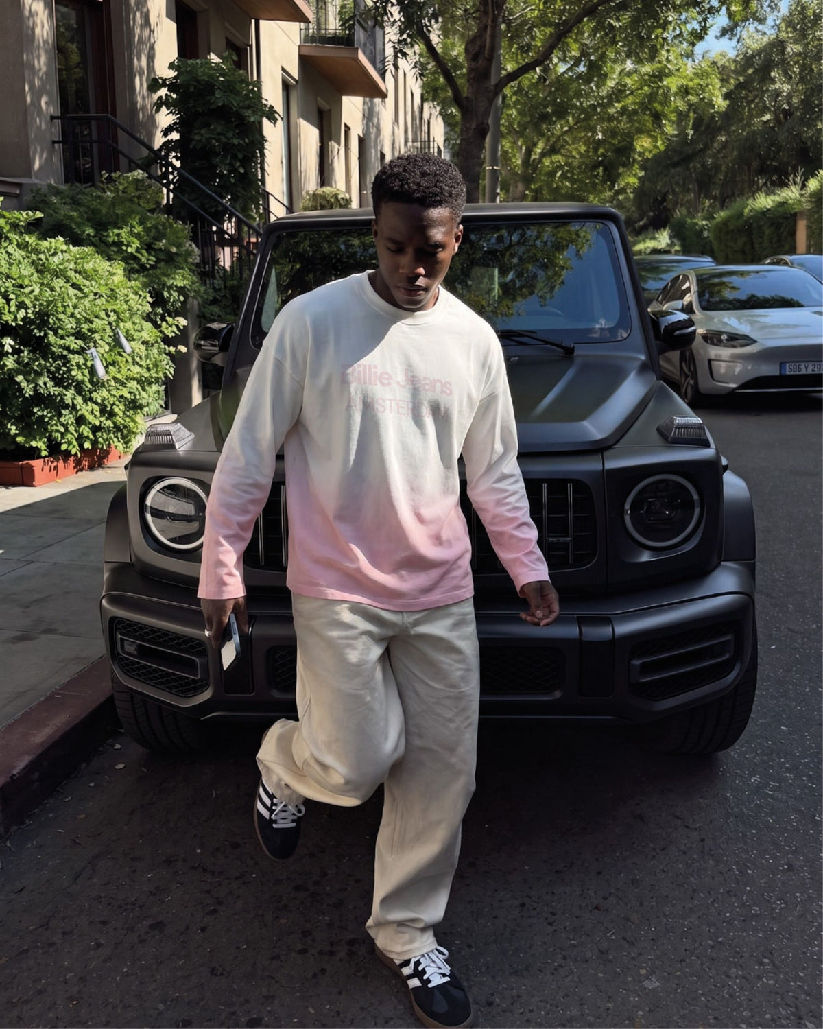Man wearing the Billie Long Sleeve Fade with beige trousers walking past a black SUV