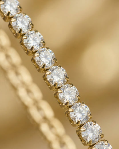 Close-up of a gold chain with round clear stones set in a row.