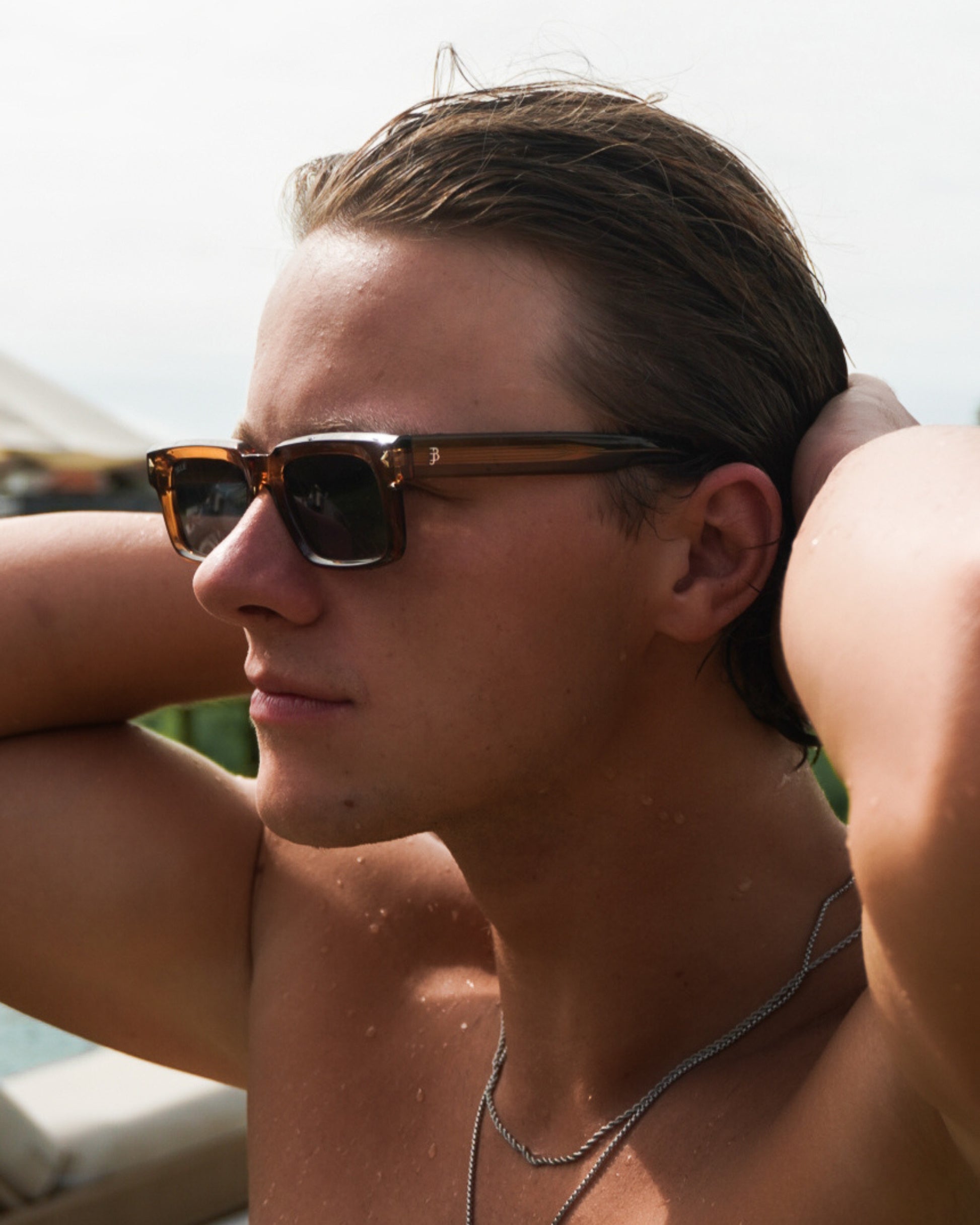 Profile of a person with sunglasses and wet hair, water droplets on skin.