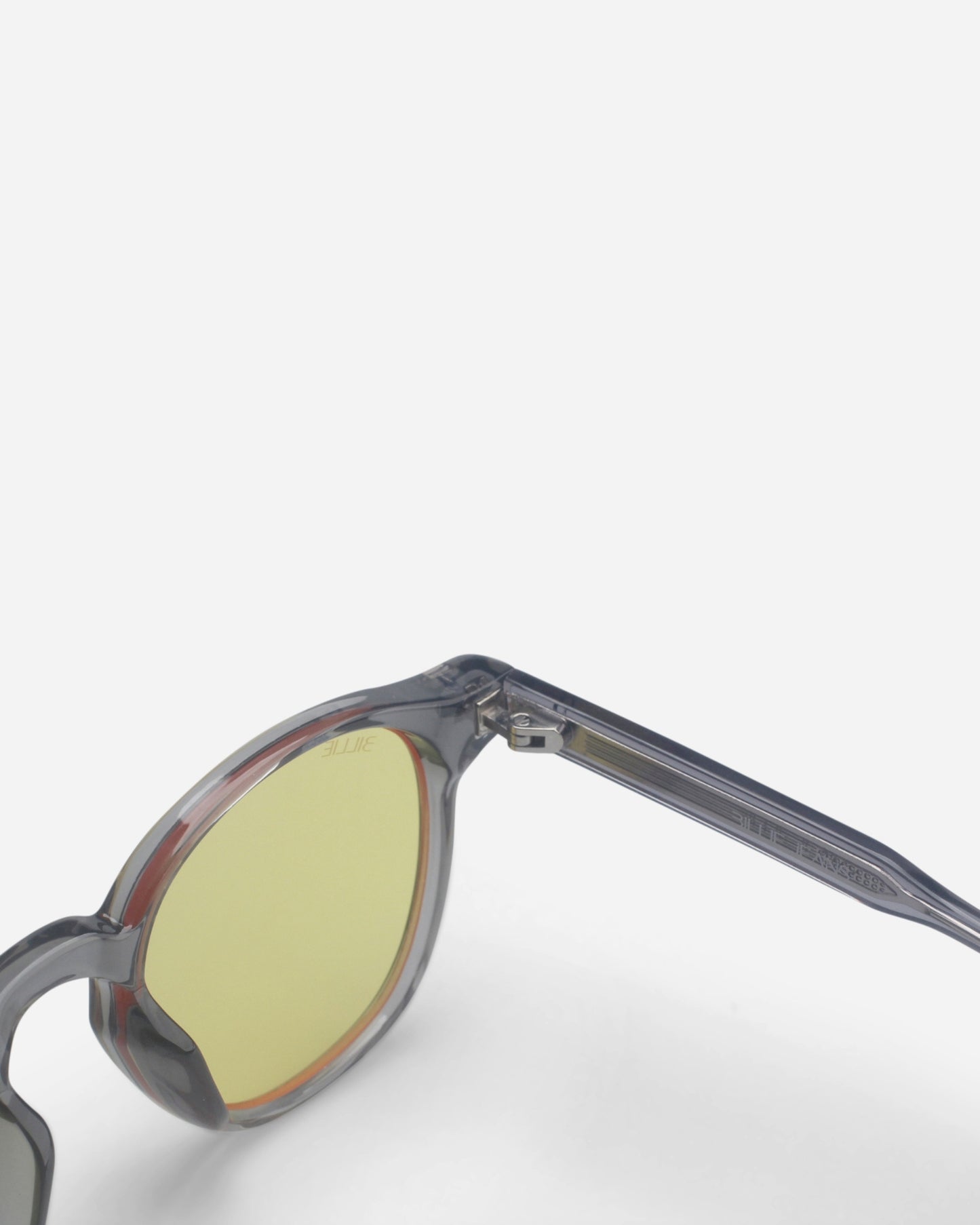 Close-up of sunglasses with gray frame and yellow lenses on a plain background.