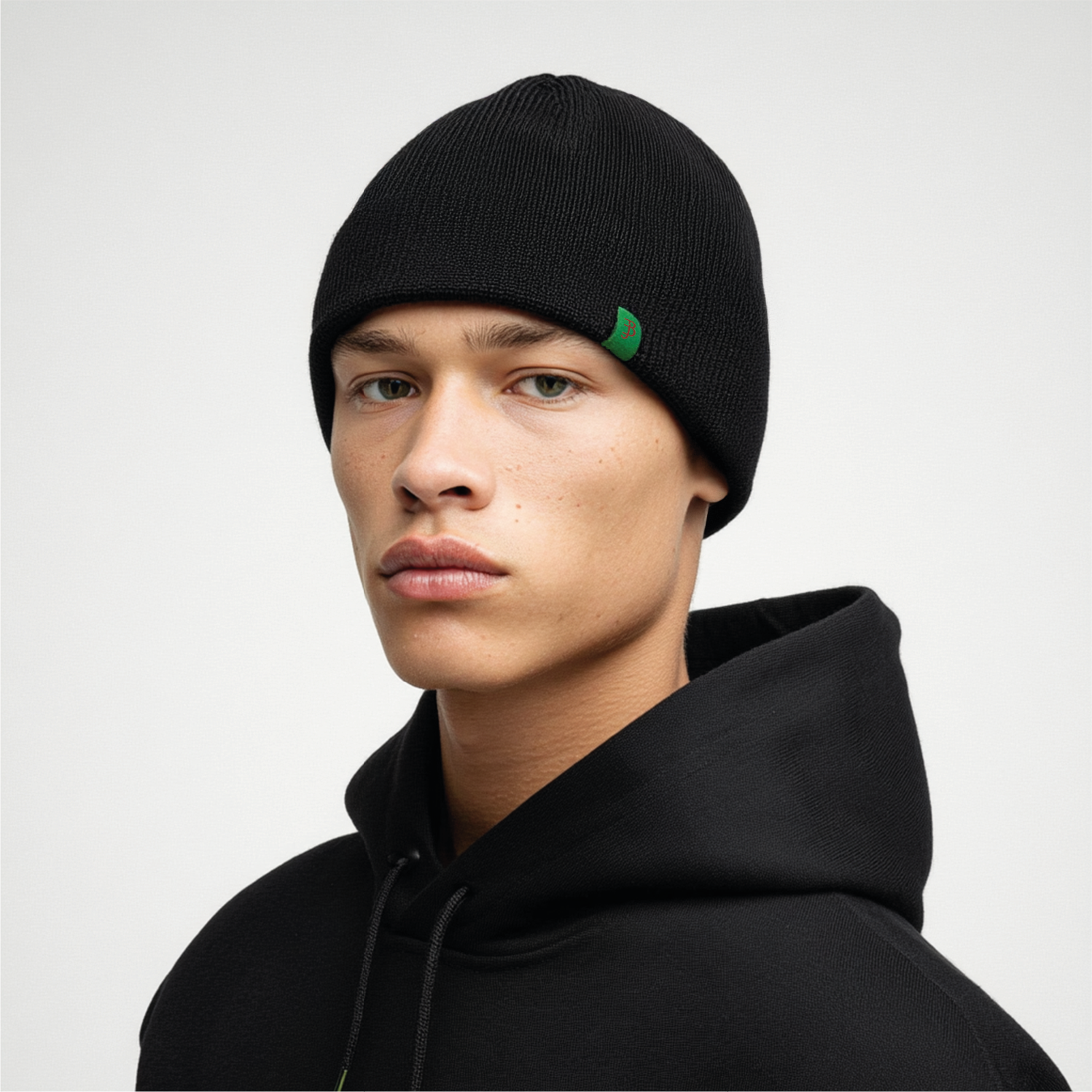 Person wearing a black beanie with a green logo on a white background