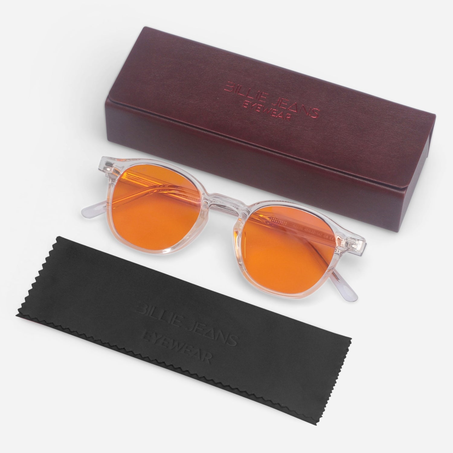 Round orange sunglasses with clear frames on a white background, accompanied by a brown case and black cleaning cloth.