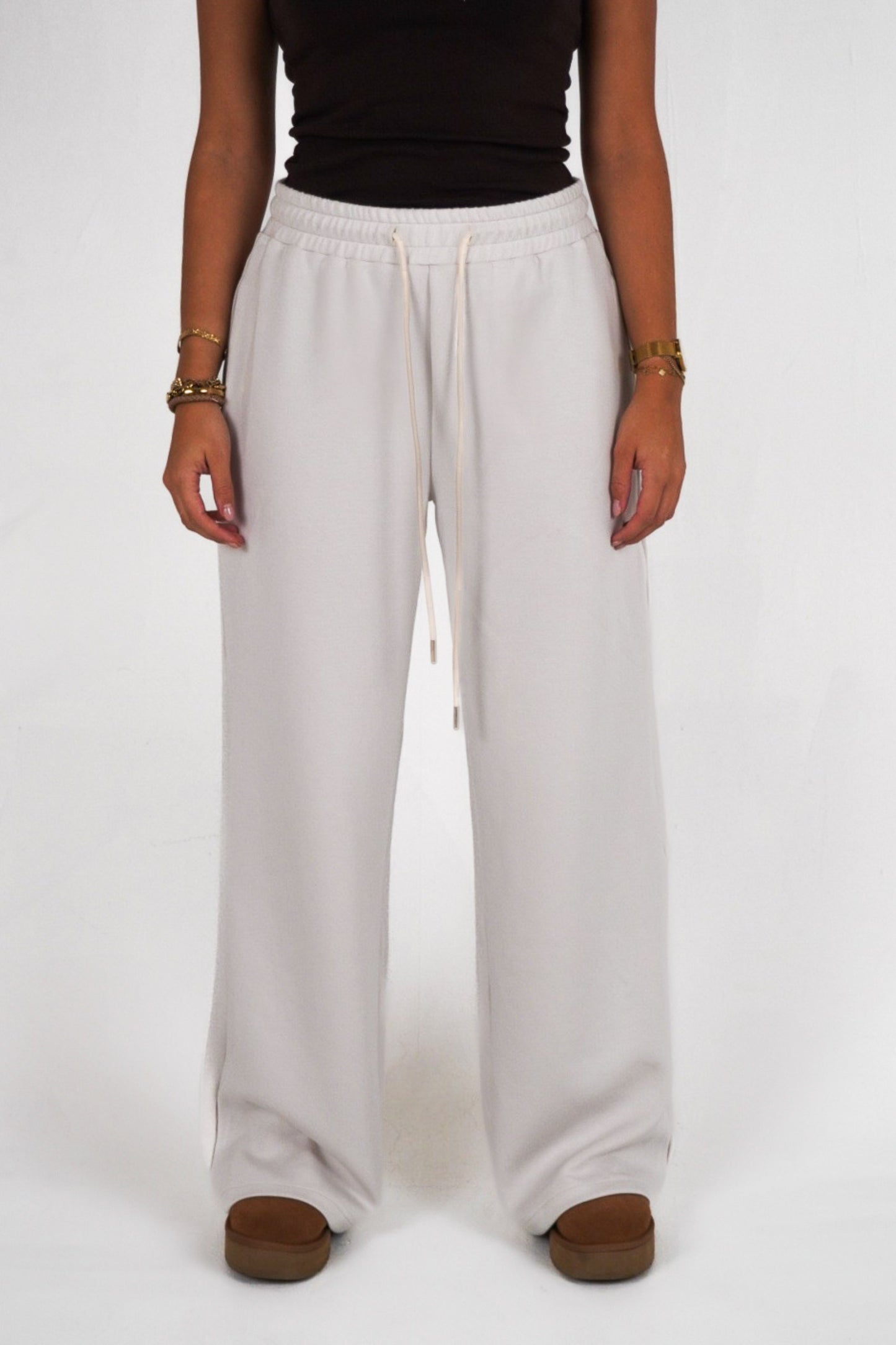 Person wearing light gray wide-leg pants on a white background