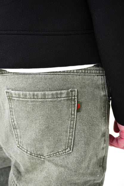 Person wearing green jeans with a brand logo on the back pocket against a white background