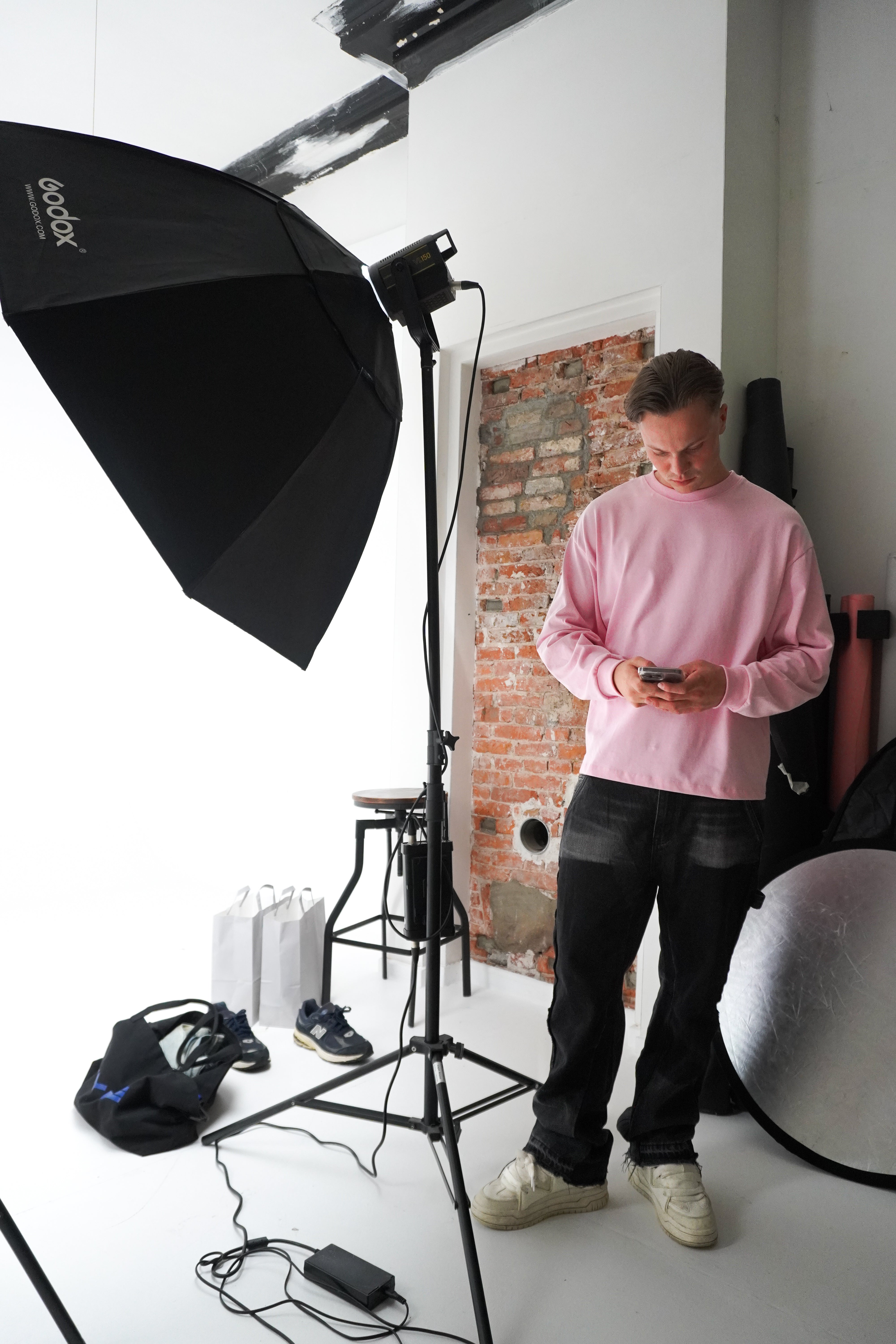 Person in a pink sweater standing in a photography studio with lighting equipment.