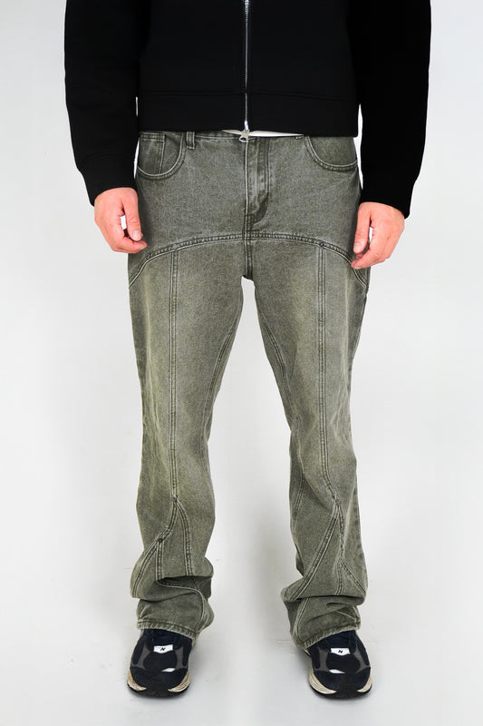 Person wearing green jeans and black shoes on a white background