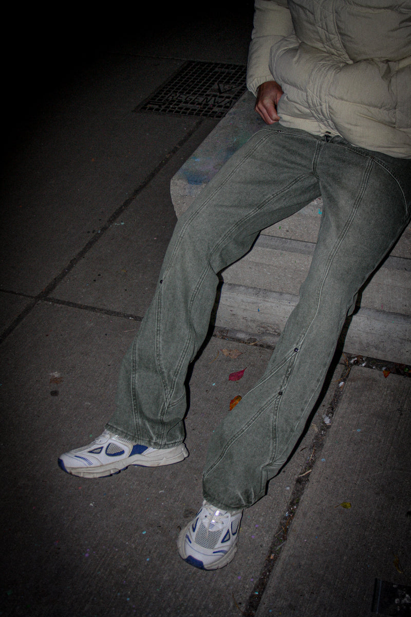 Person sitting on a step wearing green pants and white sneakers at night.