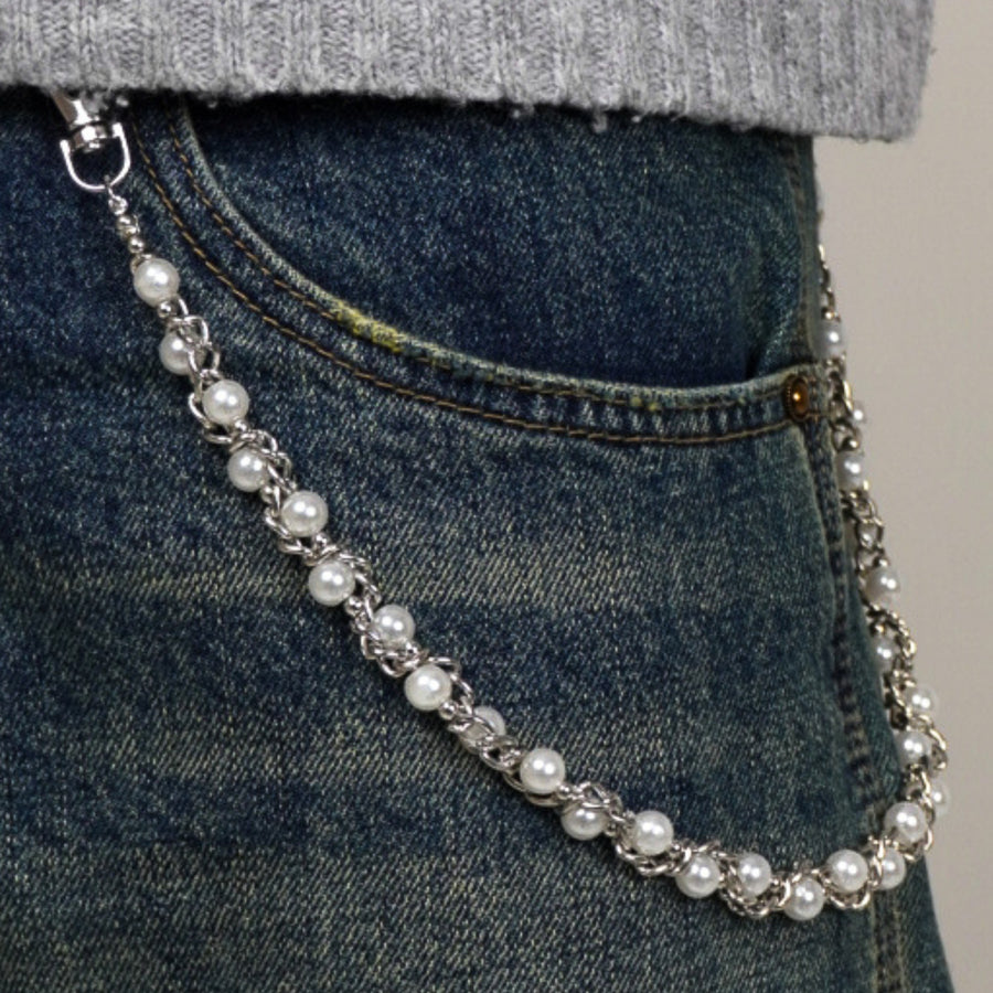 Pearl chain accessory draped over a person wearing jeans and a gray sweater.