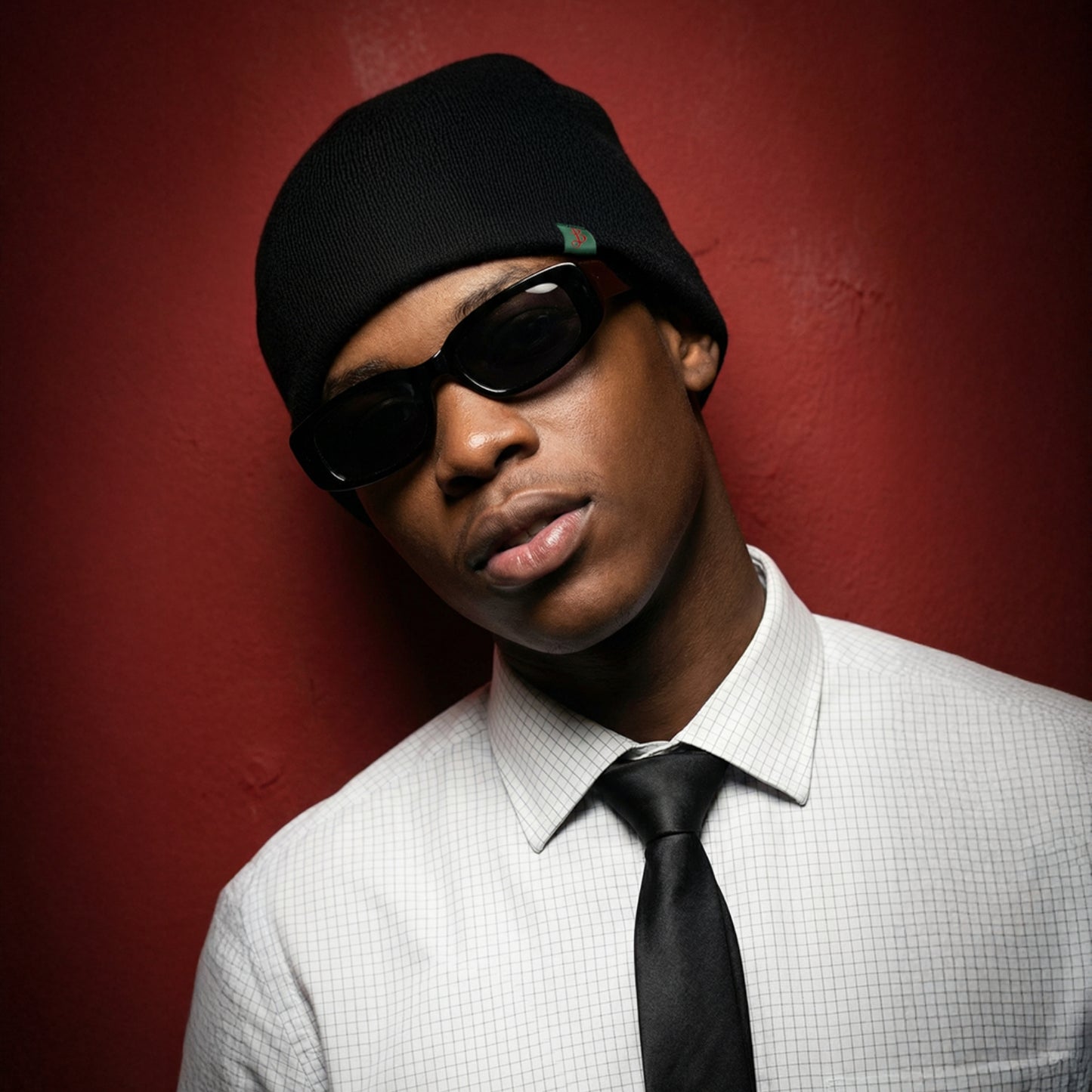 Man wearing a black beanie and sunglasses against a red background