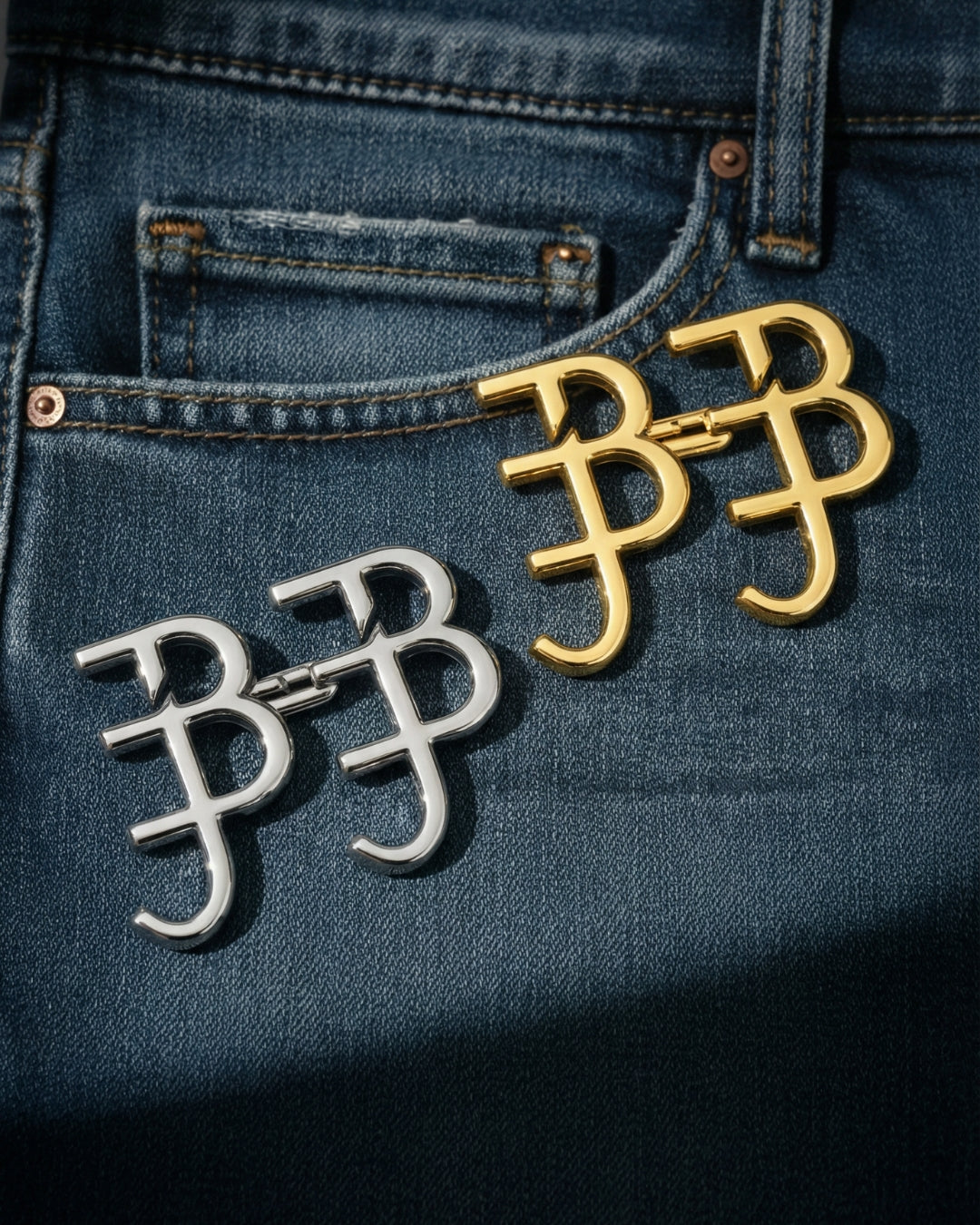 Two pairs of gold and silver letter 'B' waist knots on a blue denim background
