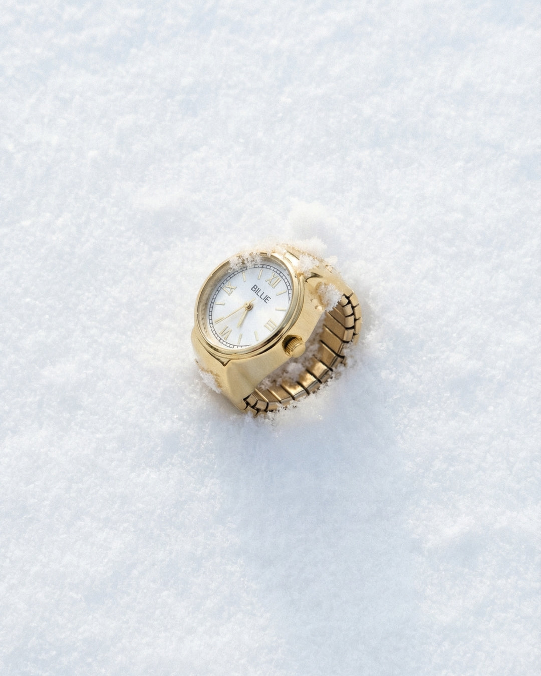 Gold watch on a textured white surface