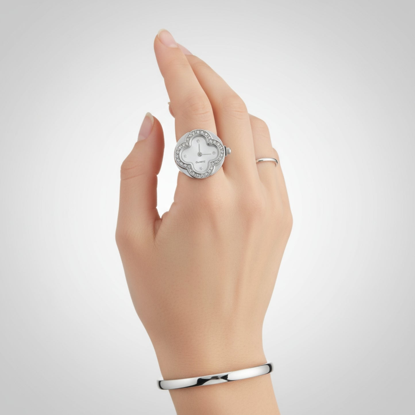 Hand wearing a silver ring with a diamond design on a light gray background