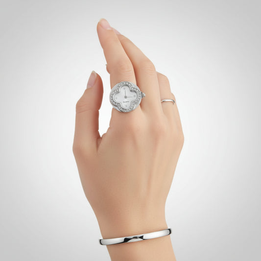 Hand wearing a silver ring with a diamond design on a light gray background