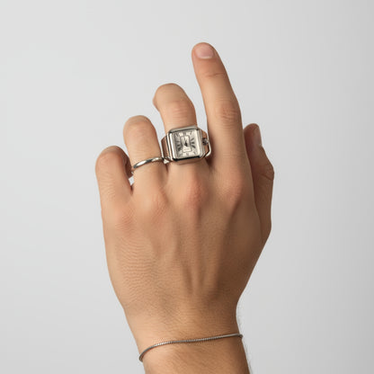 Hand wearing two rings on a plain background