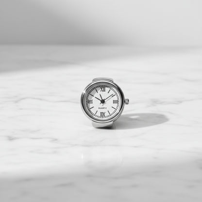 Silver ring watch with a white face on a light gray background