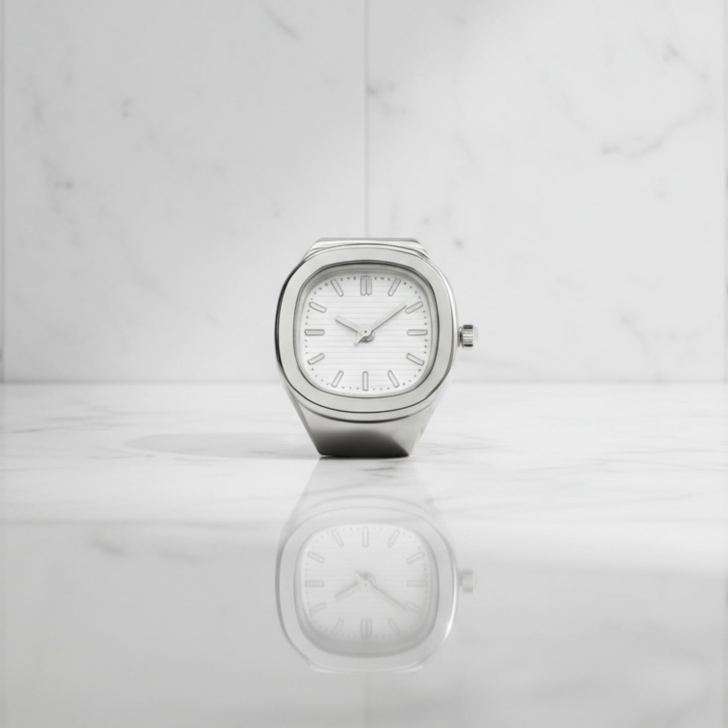 Silver ring watch with a white face on a light gray background