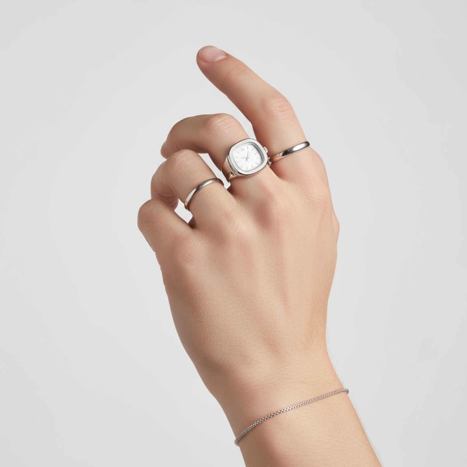 Hand wearing two silver rings on a light gray background