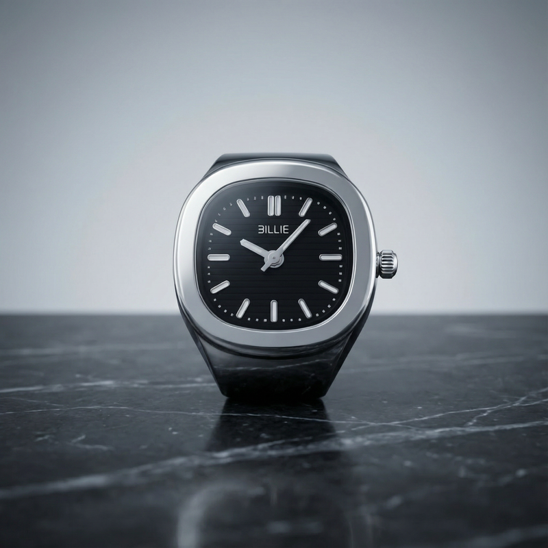 Silver watch with black face on a dark surface and gray background