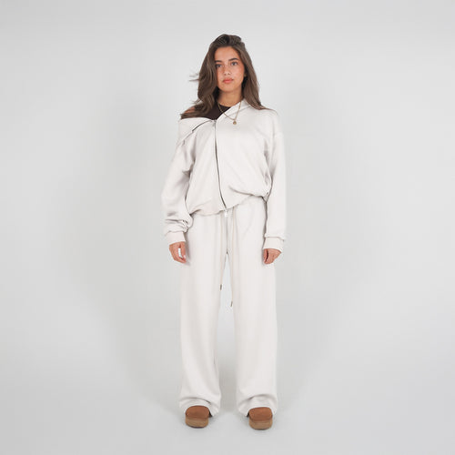 Person wearing a white tracksuit on a plain background